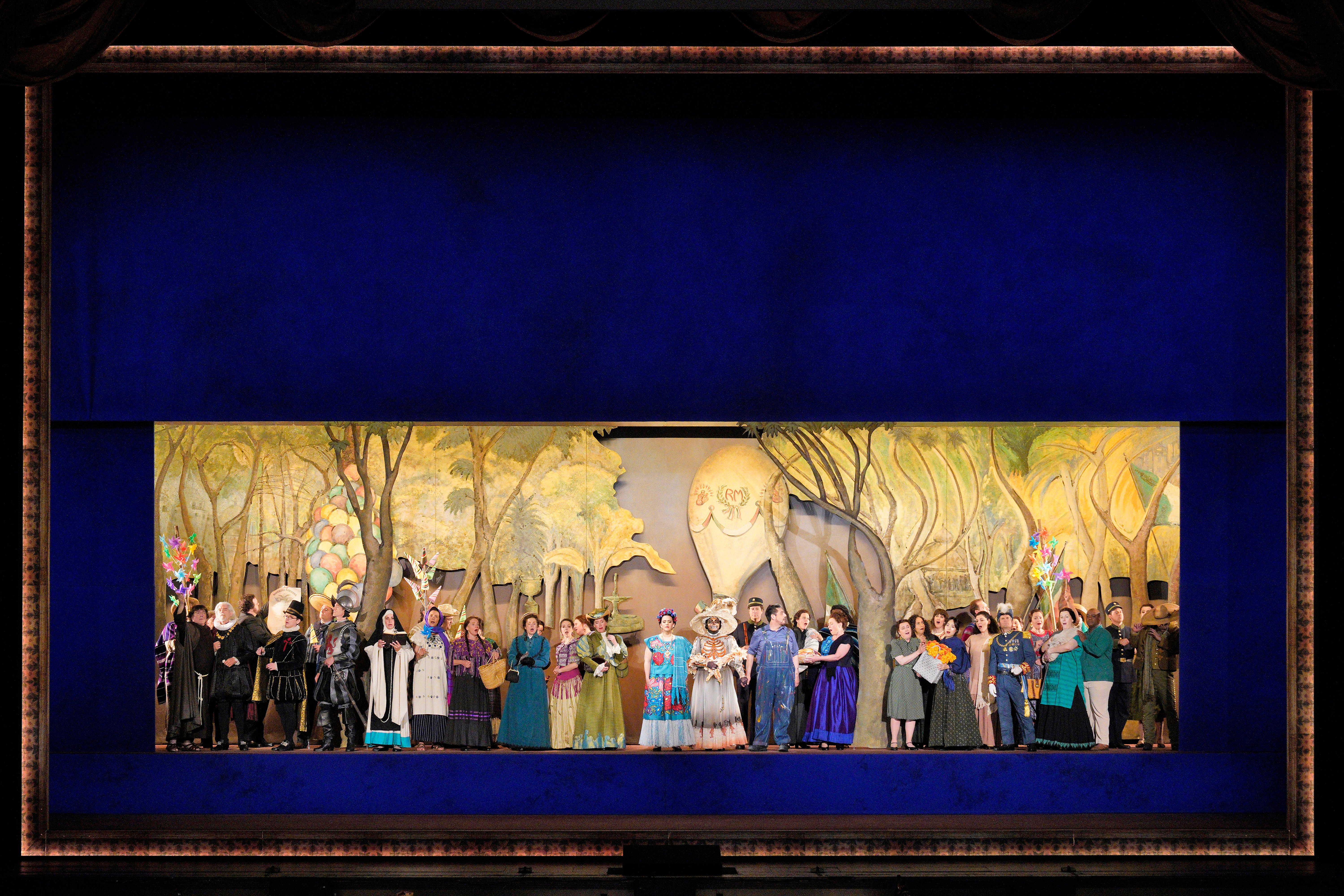 Scene from Frida A group of people standing on stage in front of a painting of a forest