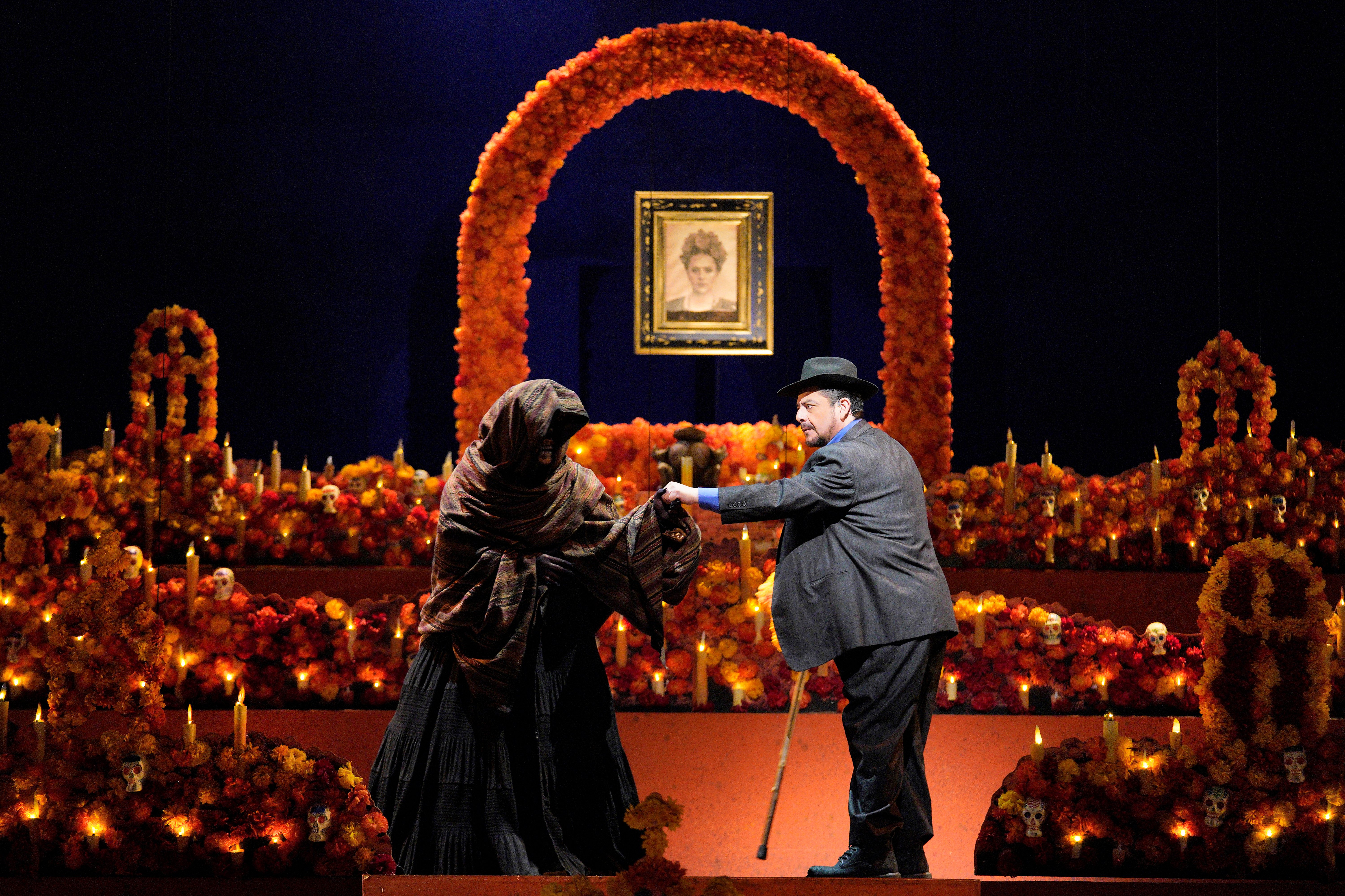 Scene from Frida of a man speaking with a person cloaked in black