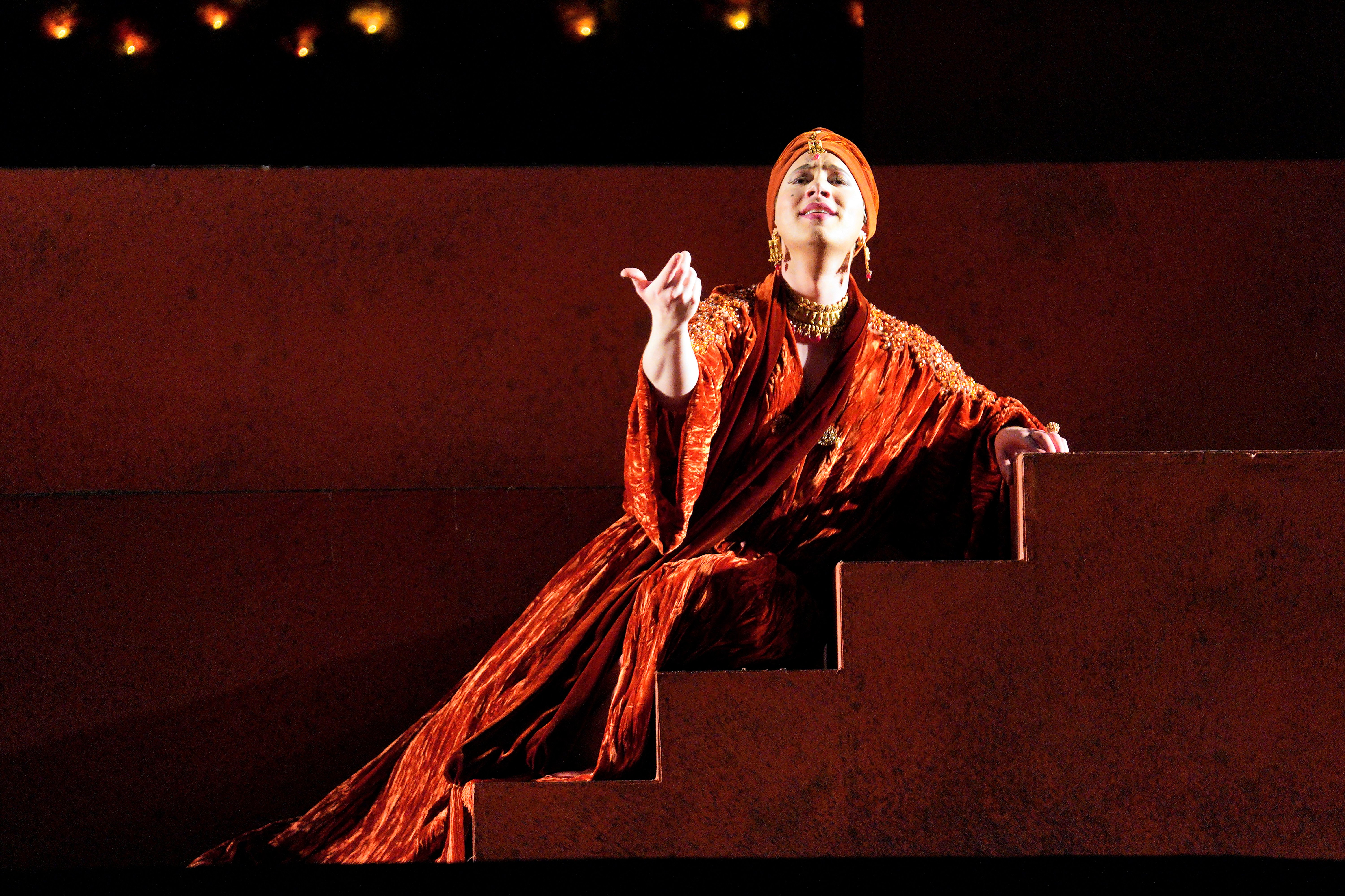 Scene from Frida A woman in a red dress sitting on steps.