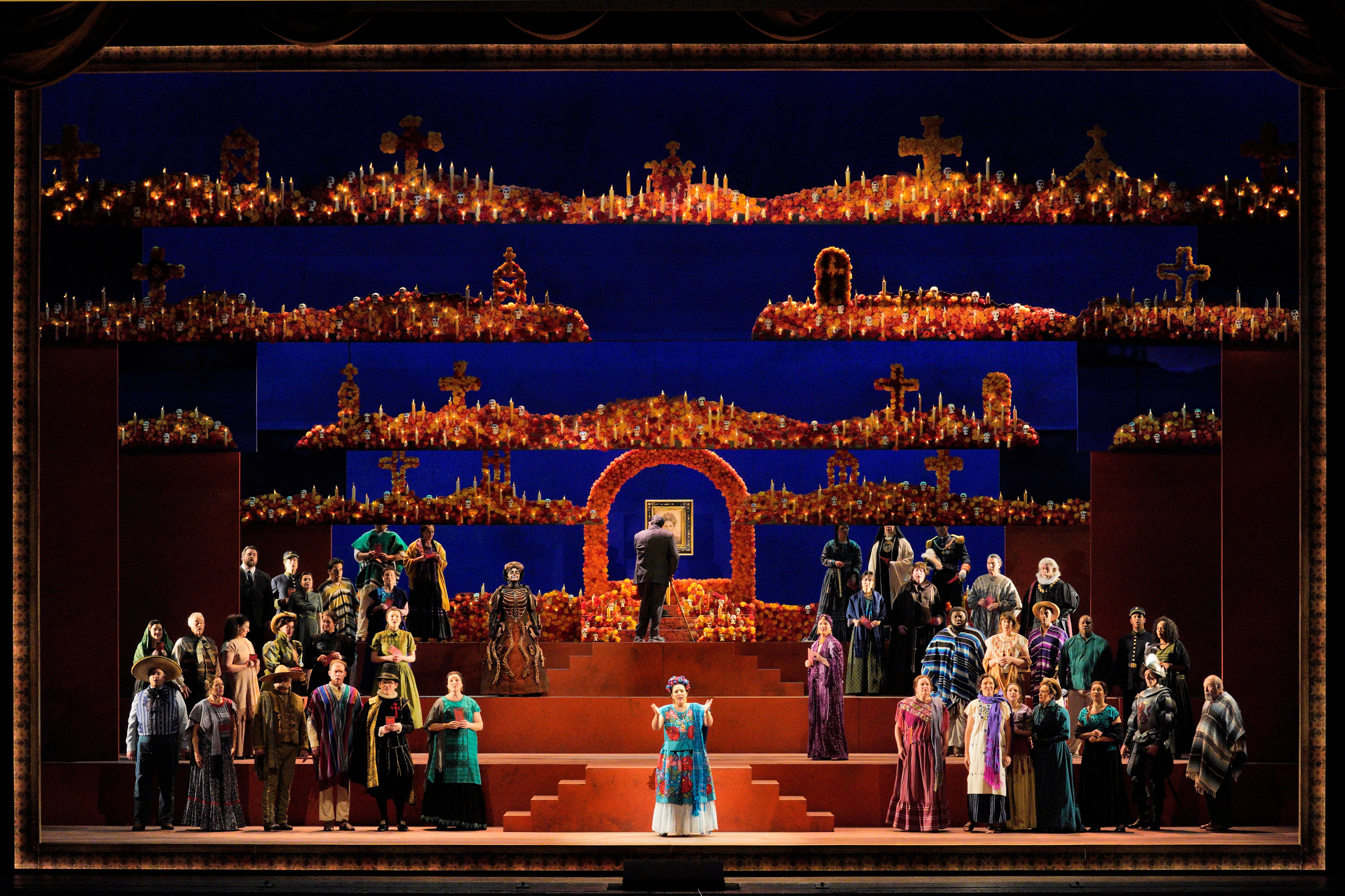 Scene from Frida A group of people standing on stage in front of a large stage.