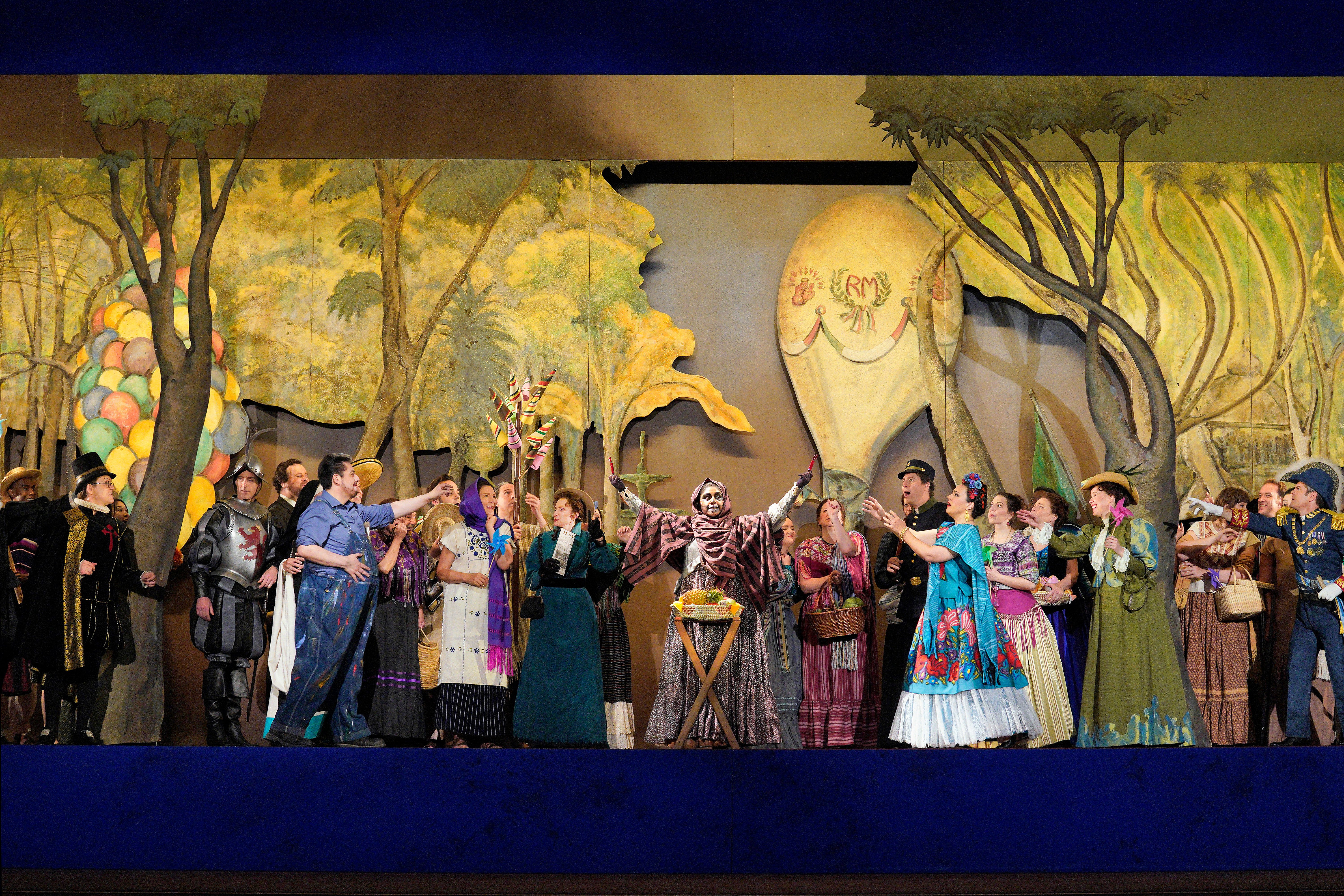 Scene from Frida A group of people standing on stage in front of a painting of forest with a person in skeleton costume at the center