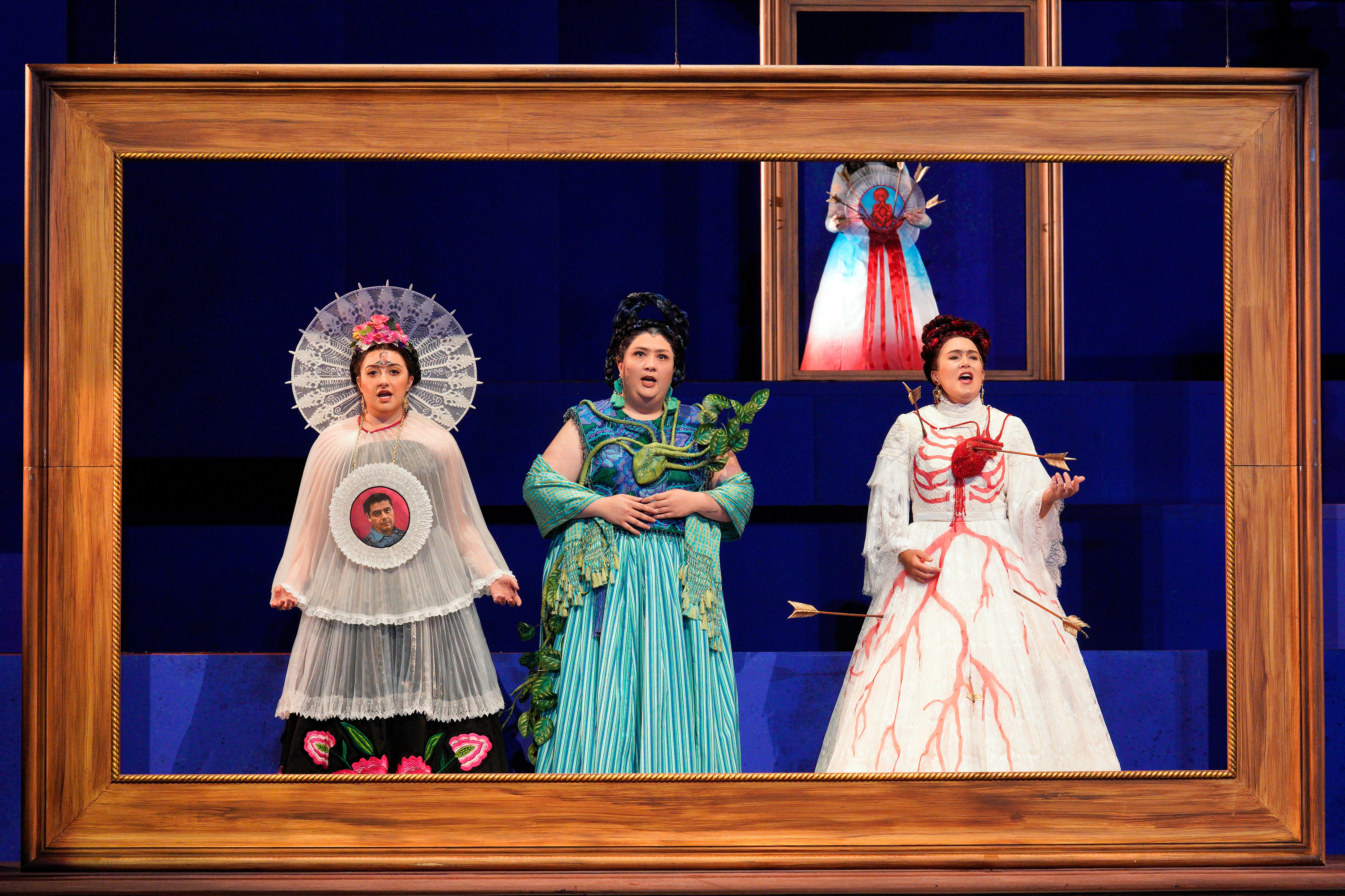 Scene from Frida of three women singing while standing inside a picture frame