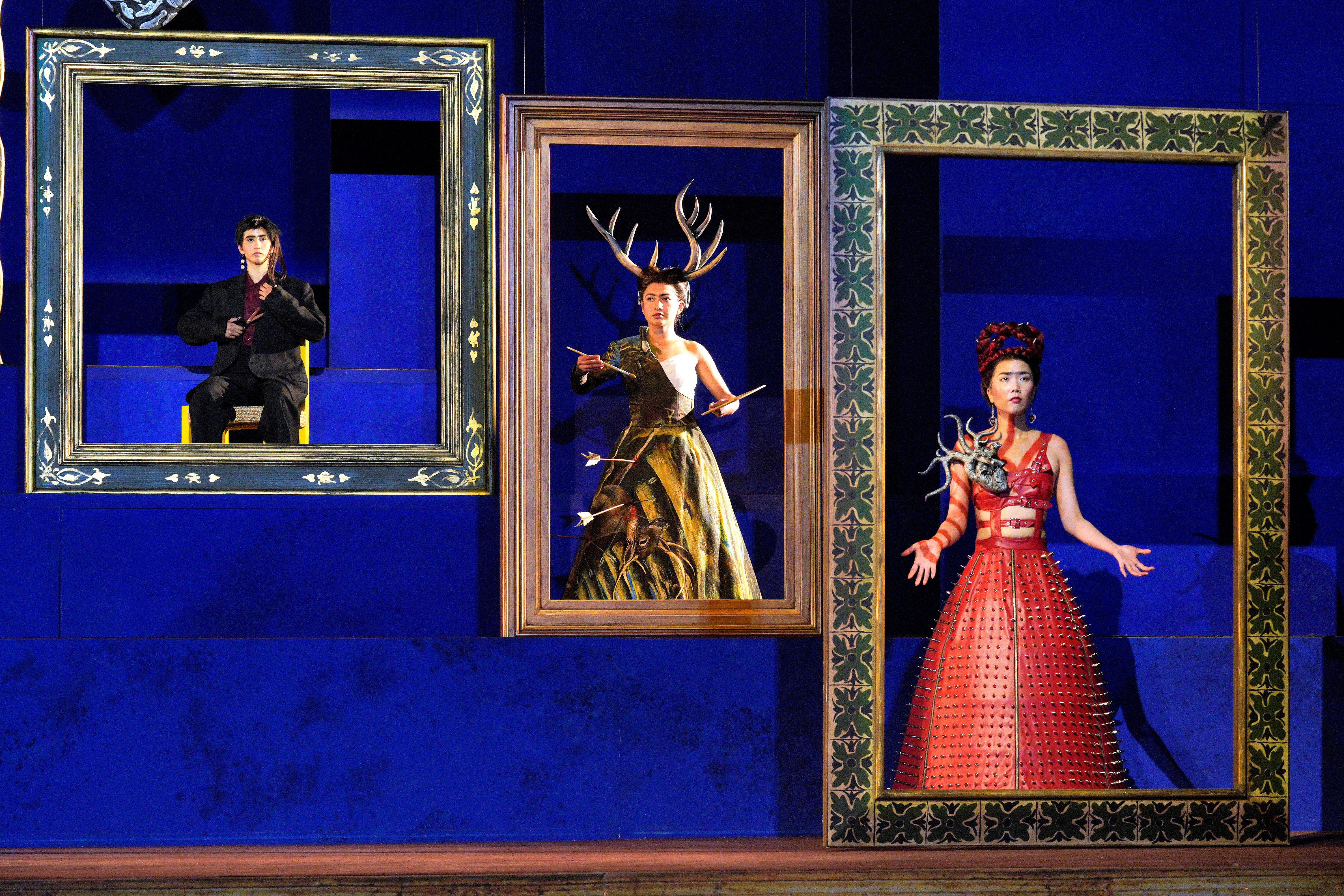 Scene from Frida of three people each standing inside a picture frame